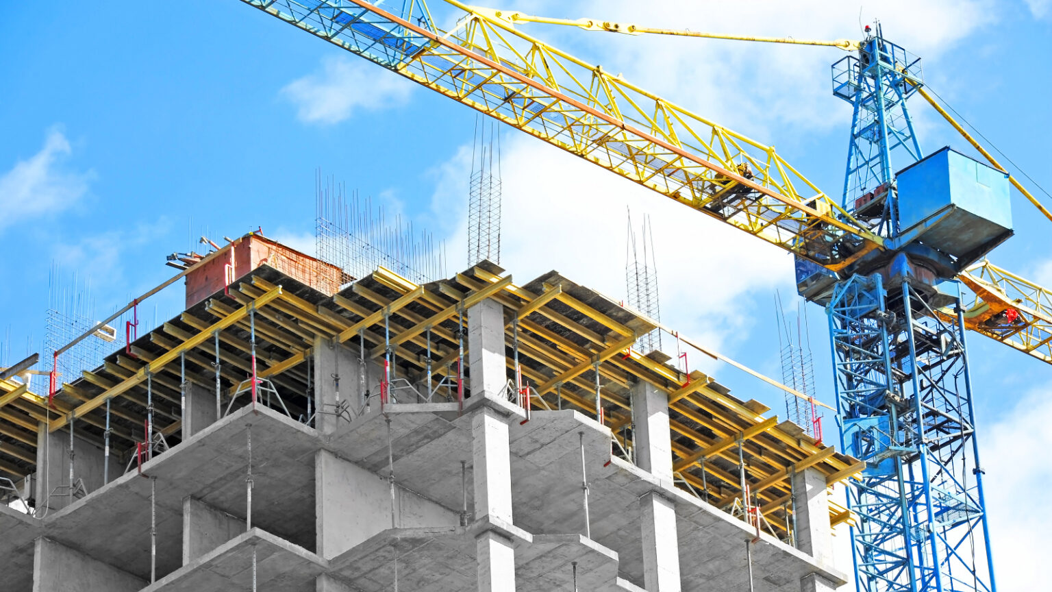 Crane and building under construction against blue sky