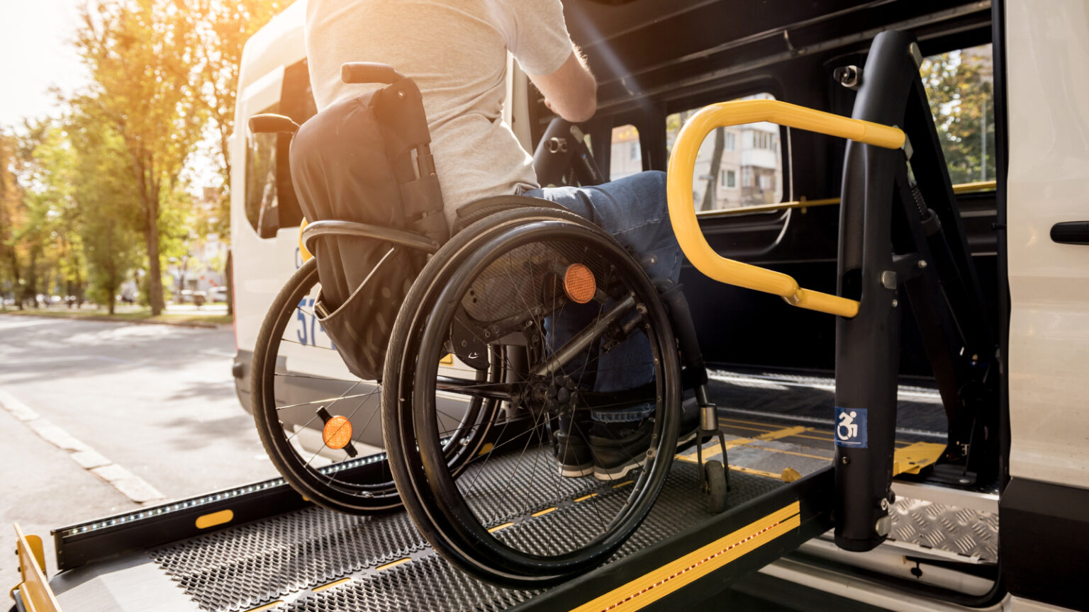 A man in a wheelchair on a lift of a vehicle for people with disabilities