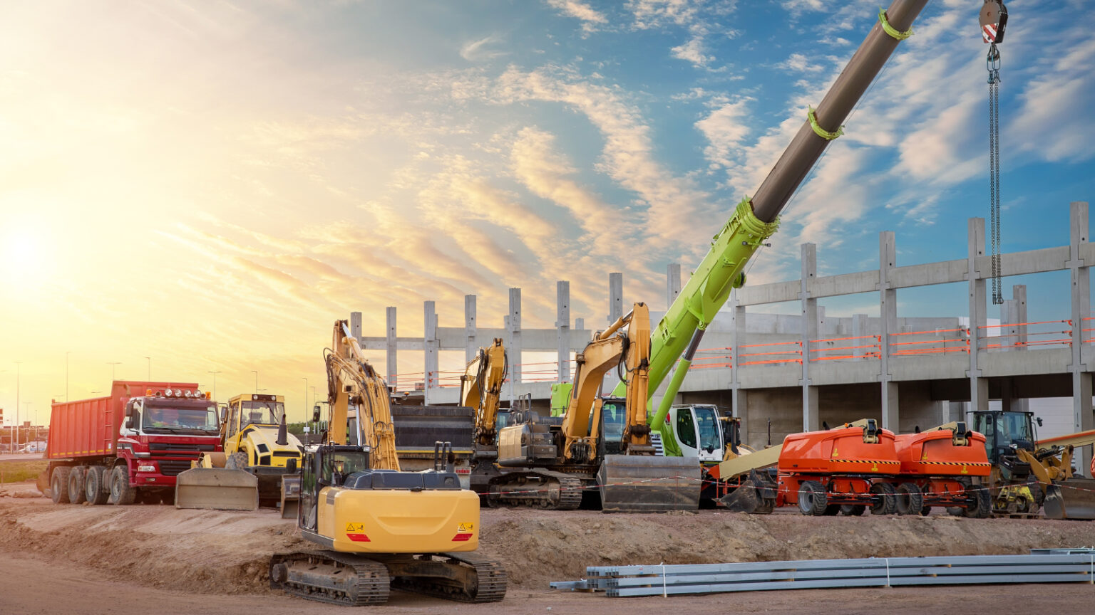 Many different multiclored colorful heavy industrial machinery equipment at construction site parking area against warehouse building city infrastructure development. Commercial vehicles rental sale